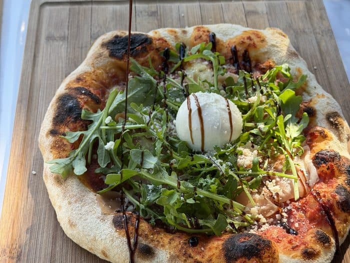 Fertige Pizza mit leopardiertem Rand auf dem Brett