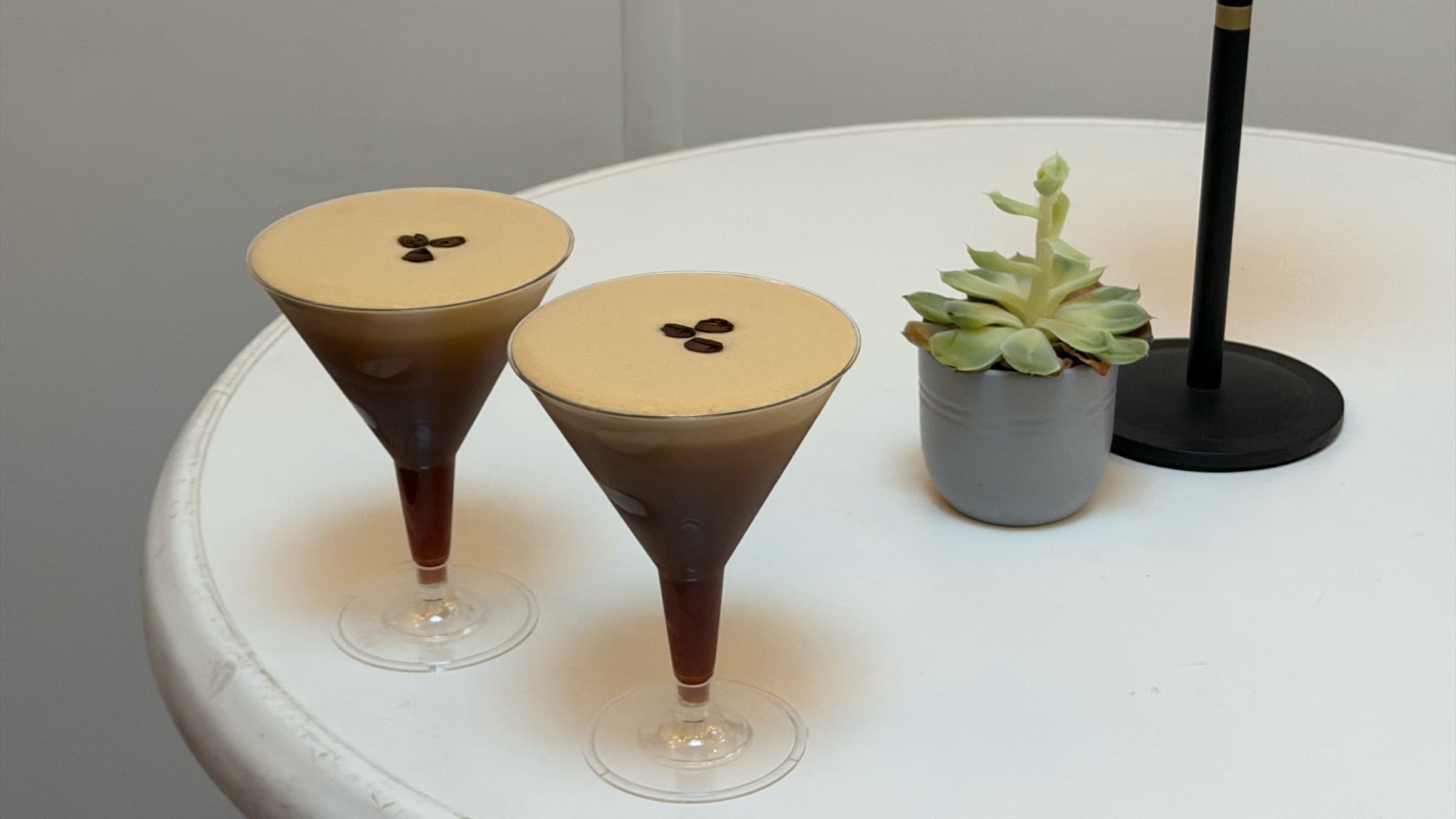 Zwei Espresso Martinis mit je drei Kaffeebohnen auf einem weißen Bistrotisch
