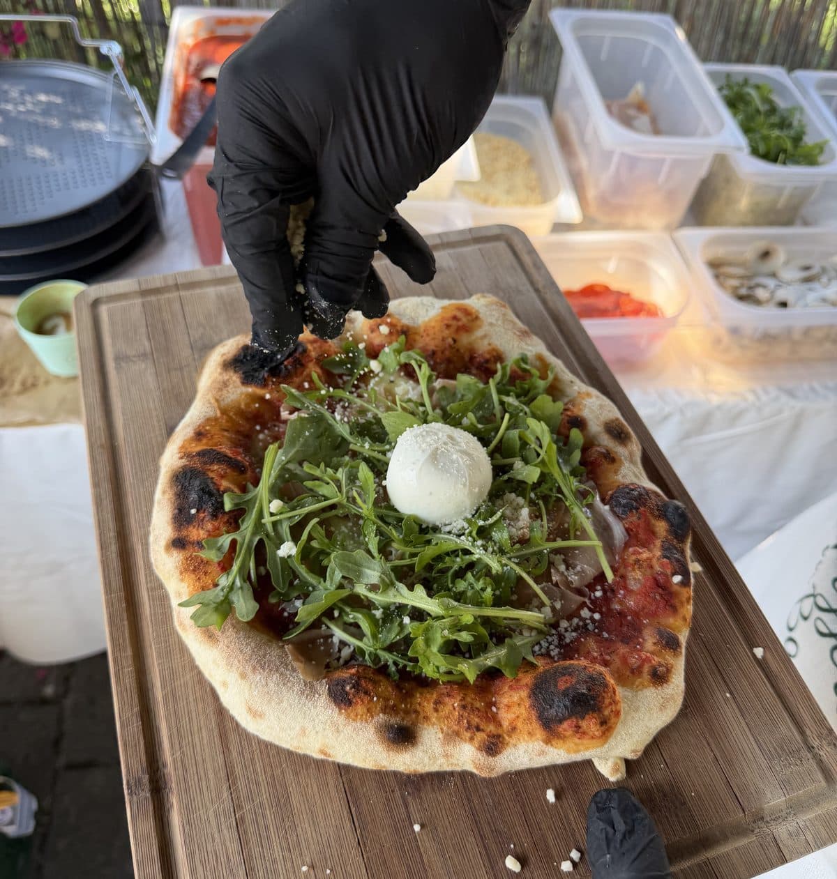 Pizza wird bei einem Event vor Ort mit Rucola und Burrata belegt