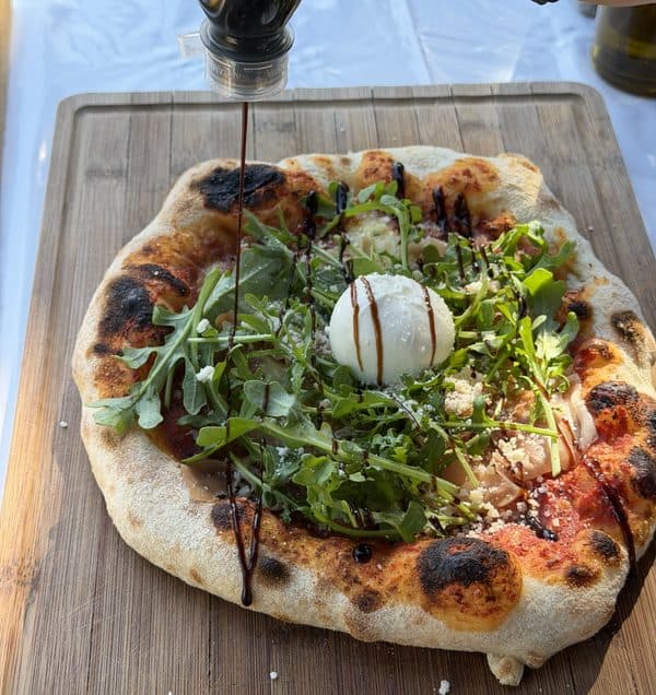 Fertige Pizza mit leopardiertem Rand auf dem Holzbrett