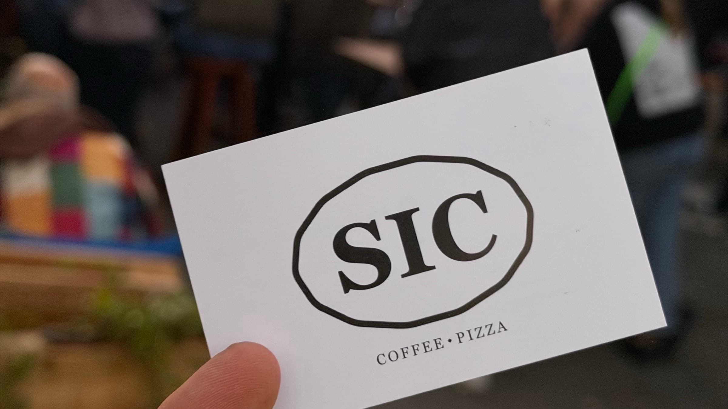 SIC Coffee Pizza Visitenkarte vor einer Gruppe von Firmengästen