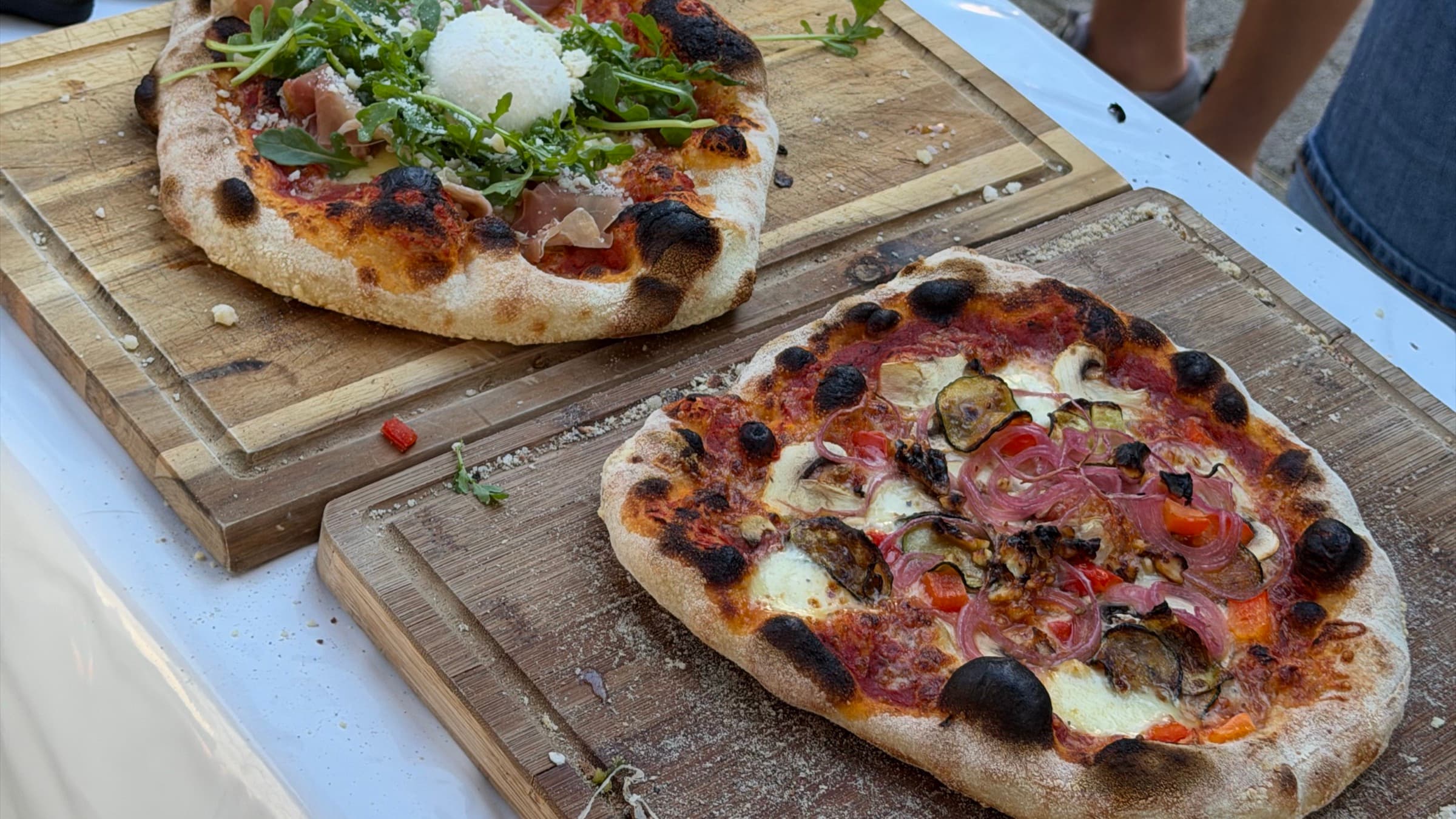 Zwei frisch gebackene Pizzen auf Holzbrettern beim Event-Catering